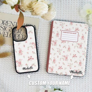 May include: Two personalized items with a floral pattern. A white phone case with a black border and the name "Michelle" printed on it. A white composition book with a red spine and the name "Michelle" printed on it.