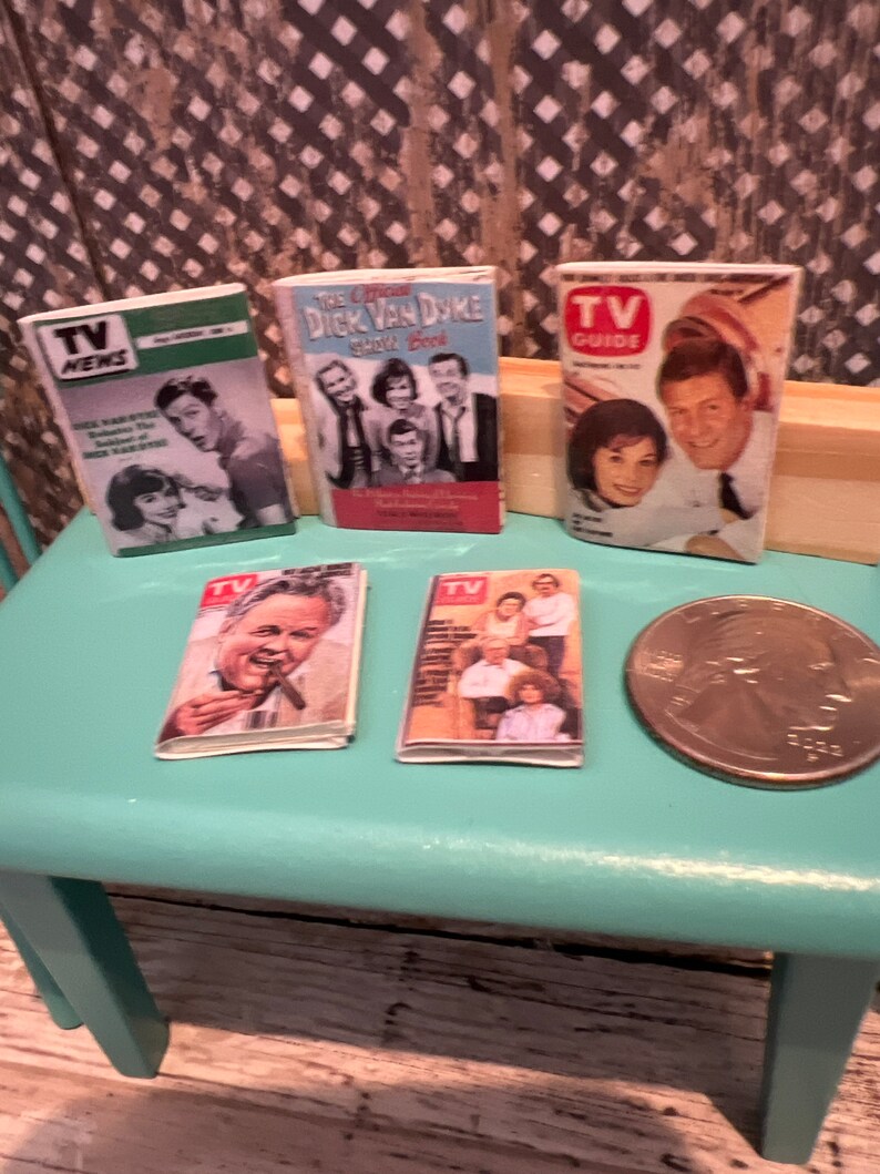 Puede incluir: Cinco revistas en miniatura de TV Guide vintage sobre una mesa turquesa con una moneda de veinticinco centavos de d&oacute;lar de plata. Las revistas presentan portadas con fotos de Dick Van Dyke,  "TV Guide" y "TV News".