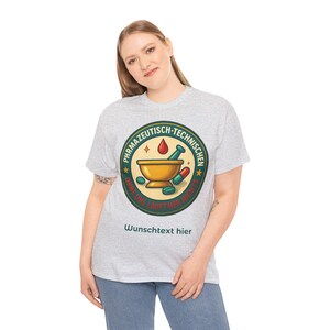 Op de afbeelding: Lichtgrijs t-shirt met een cirkelvormige afbeelding. De afbeelding bevat de woorden "PHARMAZEUTISCH-TECHNISCHEN" en "OHNE UNS LÄUFT HIER NICHTS". Het bevat een vijzel en stamper, pillen en een druppel. De tekst "Wunschtext hier" staat eronder.