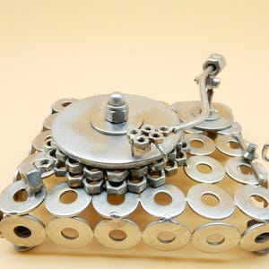 May include: A silver metal sculpture of a record player made from washers and nuts. The record player has a round turntable, a tone arm, and a base made of washers.