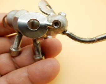 May include: A silver metal elephant sculpture made from nuts and bolts. The elephant has a long trunk and large ears.