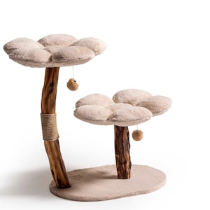 Könnte beinhalten: Ein zweistöckiger Katzenbaum mit beigefarbenen, blütenförmigen Plattformen. Der Baum hat Holzpfosten, einer mit Bindfaden umwickelt, und hängende Spielzeugbälle. Die Basis ist oval und mit passendem beigem Stoff bedeckt.