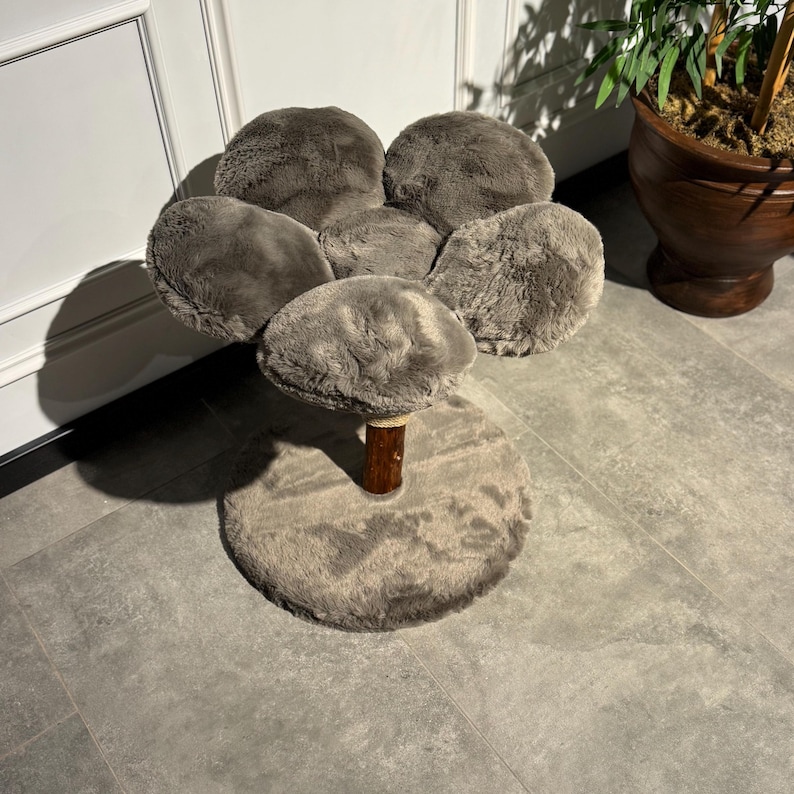May include: A gray cat tree shaped like a flower with five soft, plush petals. The tree has a brown wooden post and a round, gray base.