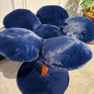 May include: A blue plush flower-shaped stool with a wooden base. The stool has five petals and a round base.