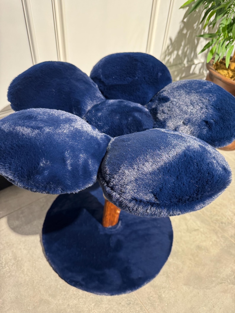 May include: A blue plush flower-shaped stool with a wooden base. The stool has five petals and a round base.