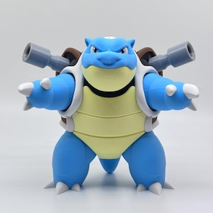 May include: A blue and yellow Blastoise figure with a brown shell and two gray cannons on its back. The figure has white accents and is posed with its arms outstretched.