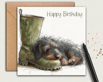 May include: A greeting card with a watercolor illustration of a dachshund dog resting on a green rubber boot. The words "Happy Birthday" are written in a script font above the dog and boot.