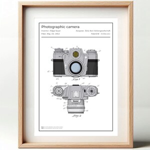 Op de afbeelding: Ingelijste print van een fotografische camera patentillustratie. De print toont twee gedetailleerde diagrammen van de camera, gelabeld "Fig. 1" en "Fig. 2", met technische annotaties. De tekst "Photographic camera" staat bovenaan, met informatie over de uitvinder en het patent.
