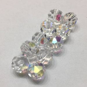May include: A cluster of clear crystal beads with iridescent facets. The beads are arranged in a loose, flowing pattern.