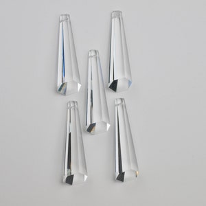 May include: Five clear glass crystal prisms, each with a pointed tip and a hexagonal base.