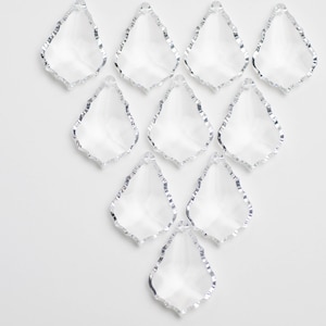 May include: Ten clear glass teardrop-shaped crystal prisms with silver-toned edges. The prisms are arranged in a triangular pattern on a white background.