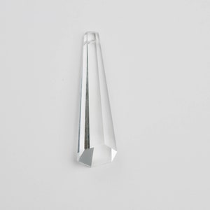 May include: A clear glass prism with a pointed top and a hexagonal base.