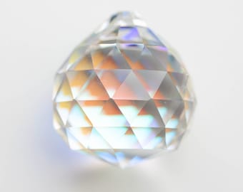 May include: A clear crystal ball with a faceted design, reflecting rainbow colors.