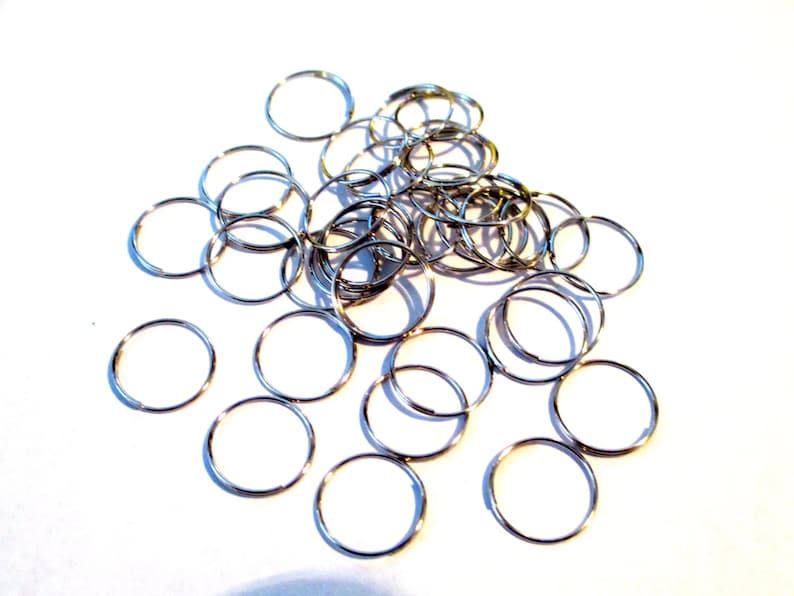 May include: A pile of silver jump rings, a type of metal ring used for jewelry making and crafting.