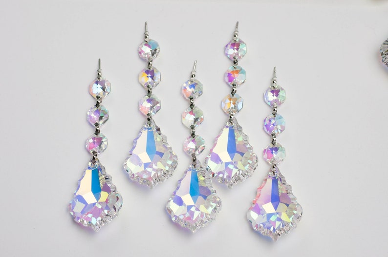 May include: Five iridescent crystal teardrop-shaped ornaments with silver accents. Each ornament has a chain of smaller crystal beads.