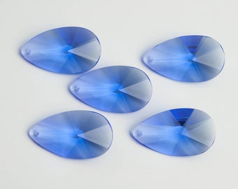May include: Five teardrop-shaped crystal beads in a light blue color. The beads are faceted and have a hole at the top for stringing.