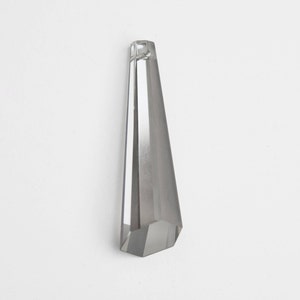 May include: A clear crystal prism pendant with a faceted design. The pendant is long and narrow, with a pointed tip.