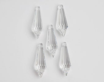 May include: Five clear crystal teardrop-shaped pendants with faceted edges.