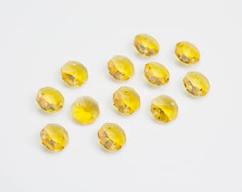 May include: A collection of 12 amber-colored faceted crystal beads. The beads are round and have a smooth, polished finish.