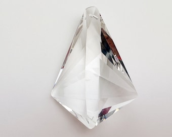 May include: A clear crystal prism pendant with a faceted design. The prism is shaped like a diamond and has a hole at the top for hanging.