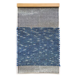 May include: A woven wall hanging with a blue and white pattern. The hanging is framed with a natural wood frame.