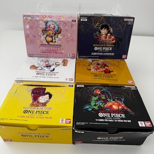 May include: Six unopened One Piece card game boxes. The boxes are in various colours, including pink, navy, yellow, and black. Each box features different character illustrations and the text "ONE PIECE CARD GAME".