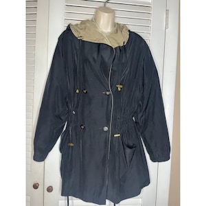 May include: Black hooded coat with a tan-colored hood lining. The coat features a double-breasted design with gold-colored buttons and toggles. It has two front pockets and a drawstring waist. The coat is displayed on a mannequin.