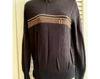 May include: Black sweater with a ribbed crew neck and hem. A horizontal band of tan stripes and a logo are across the chest. The long-sleeved sweater is made of a knit material.