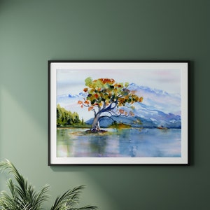 May include: Watercolour painting of a solitary tree with orange, yellow, and green leaves standing in a lake with mountains in the background.