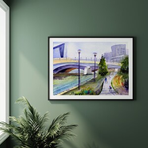 May include: Watercolor painting of a bridge over a river with a modern building in the background. People are walking and biking on the path along the river.