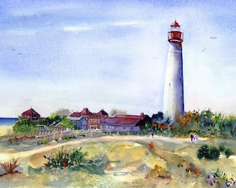 Puede incluir: Un faro blanco con un techo rojo se alza alto contra un cielo azul. El faro está rodeado de árboles y arbustos verdes. Hay varios edificios pequeños en primer plano y una playa de arena en la distancia.