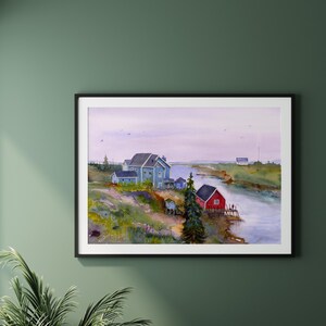 May include: A framed watercolor painting depicts a coastal scene with a river, houses, and a red building. The artwork features a blue house, a red building, and a serene sky. The painting is displayed on a green wall.