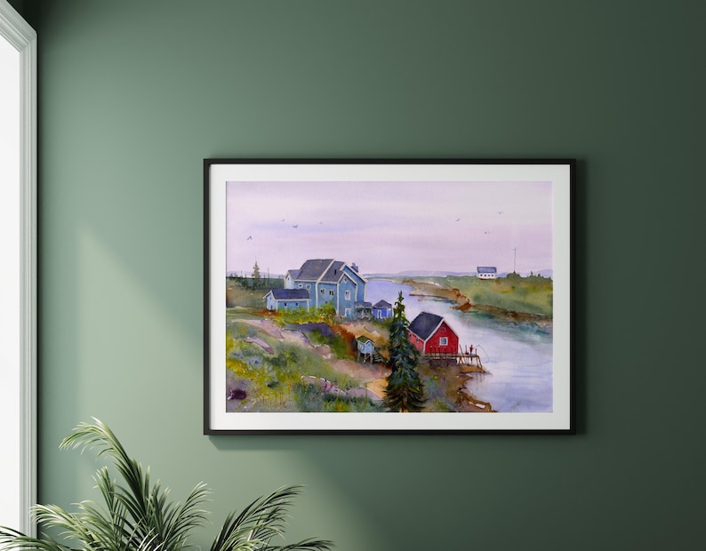 May include: A framed watercolor painting depicts a coastal scene with a river, houses, and a red building. The artwork features a blue house, a red building, and a serene sky. The painting is displayed on a green wall.