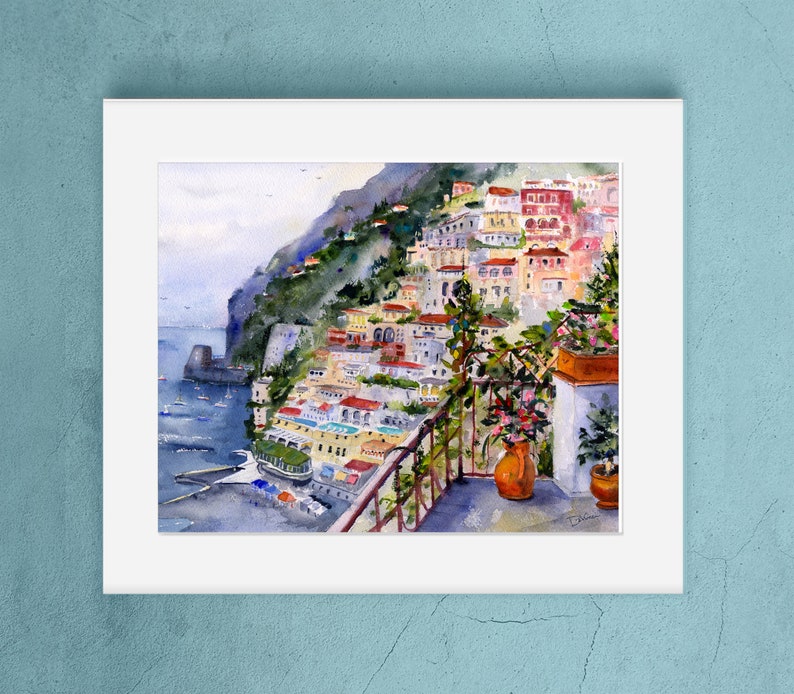 May include: Watercolor painting of a colorful Italian village on a cliffside overlooking the sea. The painting features a balcony with a potted plant and a view of the ocean.
