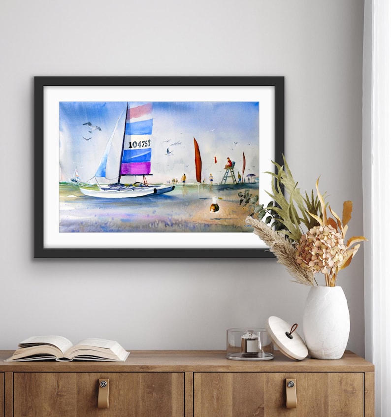 Pu&ograve; includere: Un dipinto ad acquerello di una barca a vela su una spiaggia con una torretta di salvataggio sullo sfondo. La barca a vela ha una vela blu, bianca e rosa con il numero 104753 su di essa. La torretta di salvataggio &egrave; rossa e ha una persona seduta in cima.
