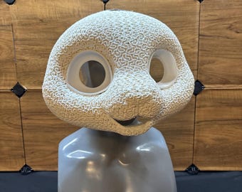 May include: A white, textured, 3D-printed animal mask base featuring large, smooth, circular eye sockets and a rounded snout. The mask has a detailed, brain-like surface pattern and is displayed on a gray, smooth, mannequin-style head bust.