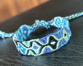 Friendship bracelet - sleeping tikis pattern in green, blue, white, and black - handmade macrame bracelet