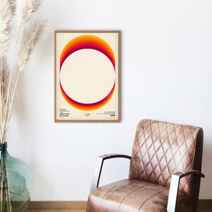 May include: A framed poster with a retro-style graphic design featuring a circle with a gradient of orange, red, and yellow colors. The text "Warsaw Autumn" is at the bottom of the poster.