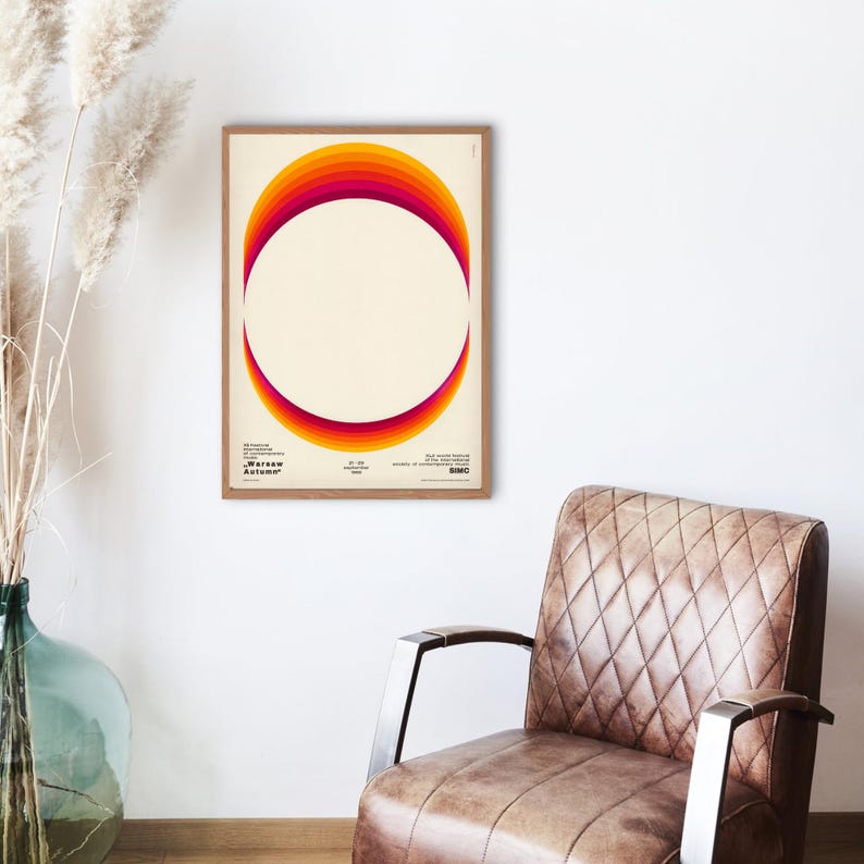May include: A framed poster with a retro-style graphic design featuring a circle with a gradient of orange, red, and yellow colors. The text "Warsaw Autumn" is at the bottom of the poster.