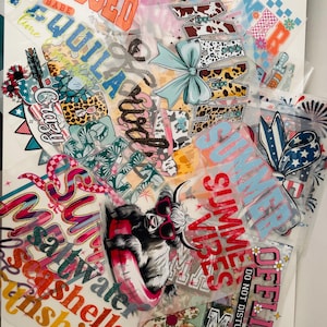 May include: A collection of iron-on heat transfer vinyl designs featuring summer-themed phrases and images. The designs include "Summer Vibes", "Sun Kissed", "Tequila", "Crazy", "Saltwater", "Seashells", "Sunshine", "Off-Line", and a Highland Cow wearing sunglasses and a float.