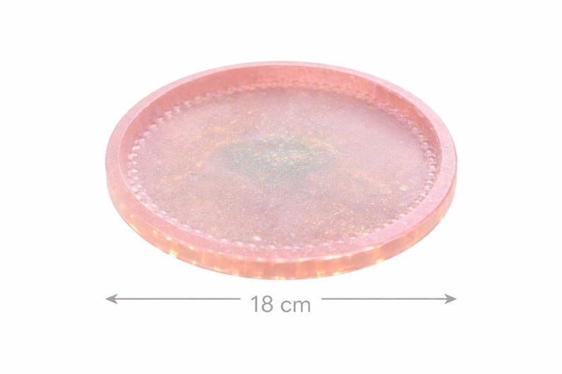 May include: A circular, pink resin tray with a beaded border. The tray measures 18 cm (7 inches) in diameter. The centre of the tray has a subtle, shimmering effect. Suitable for serving or display.