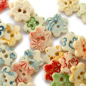 May include: Assortment of ceramic flower-shaped buttons in various colors and patterns, including blue, green, red, yellow, and white.