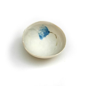 May include: A small white ceramic bowl with a blue flower design.