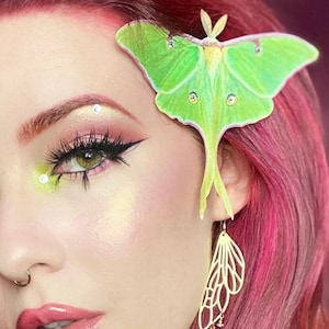 A lady with red hair and beautifully applied make up wears a silk luna moth hair clip with crystal details