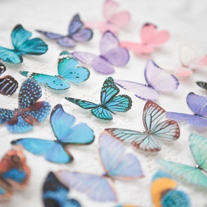 An image of a mix of pastel butterfly hair clips lined up in rows on a white vintage table cloth.