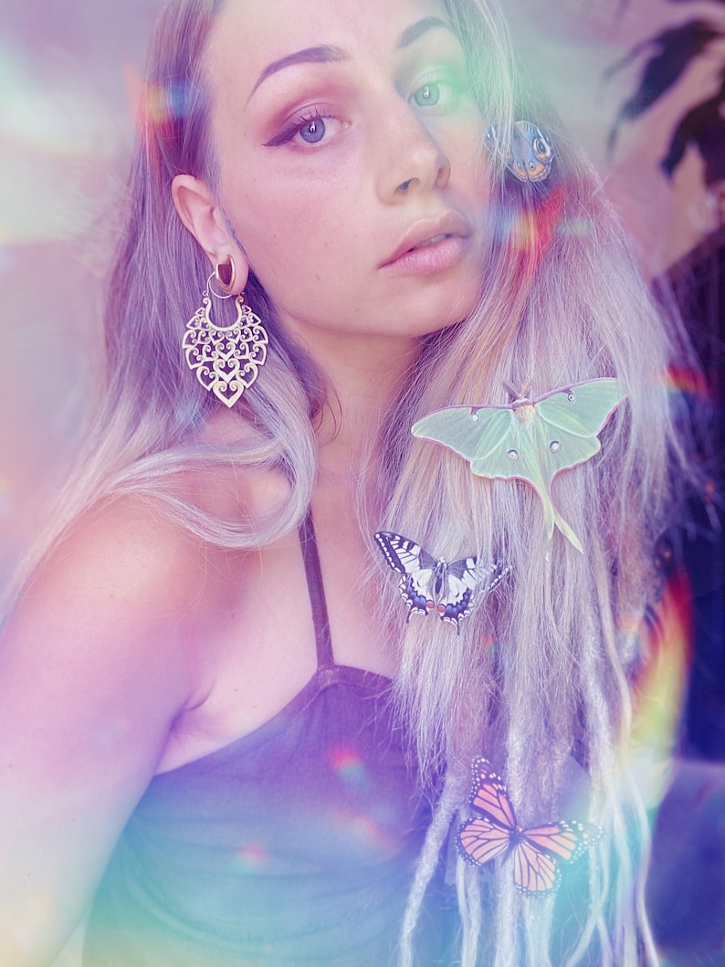 A beautiful girl with long blond hair wears silk luna moth and butterfly hair clips.