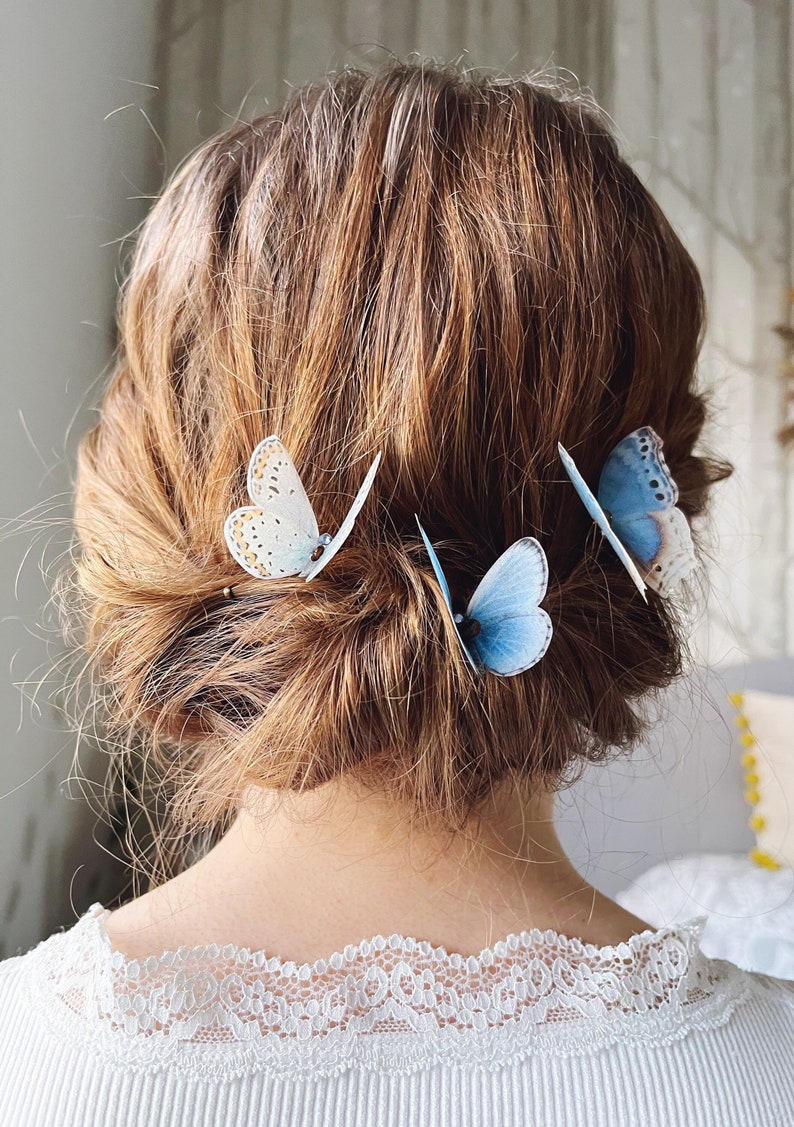 A model with a twisted chignon style up do has three pale blue silk butterflies in her hair. The butterflies are three different styles and measure about 5cm across. They look as if real butterflies have landed in her hair!