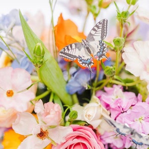 A faux swallowtail butterfly hand cut from silk sits in a beautiful pastel coloured wedding bouquet