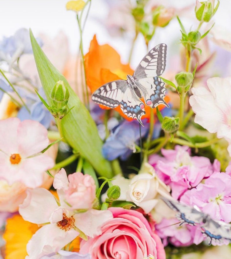 A faux swallowtail butterfly hand cut from silk sits in a beautiful pastel coloured wedding bouquet