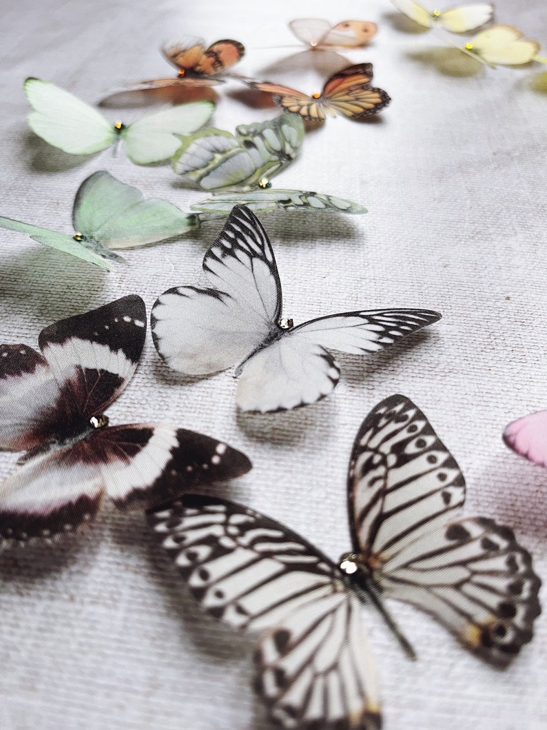 Small black and white silk butterfly hair pins rest on a neutral linen cloth. Each super realistic detailed butterfly has a tiny crystal on its head for extra sparkle.